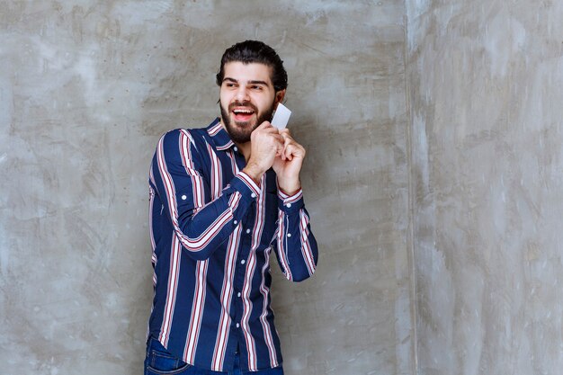 Man in striped shirt holding his business card