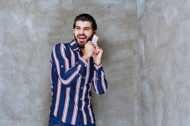 Man in striped shirt holding his business card