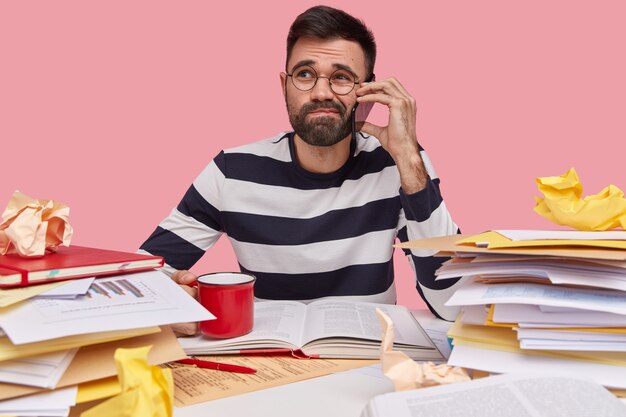 Man in striped shirt sitting at desk with documents