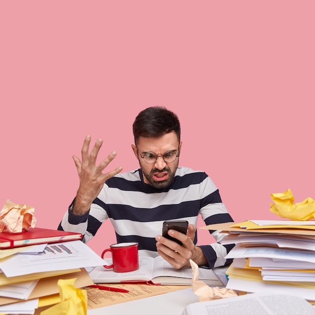 Free photo man in striped shirt sitting at desk with documents