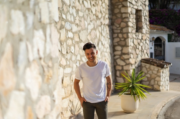 a man in a striped shirt, wearing a straw hat, walks through the streets of a small spanish town.