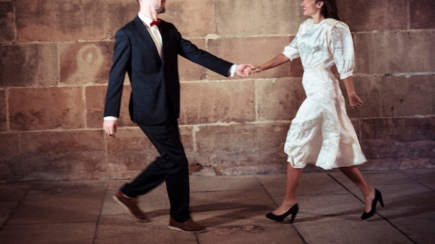 Free photo man in suit dancing with woman in street