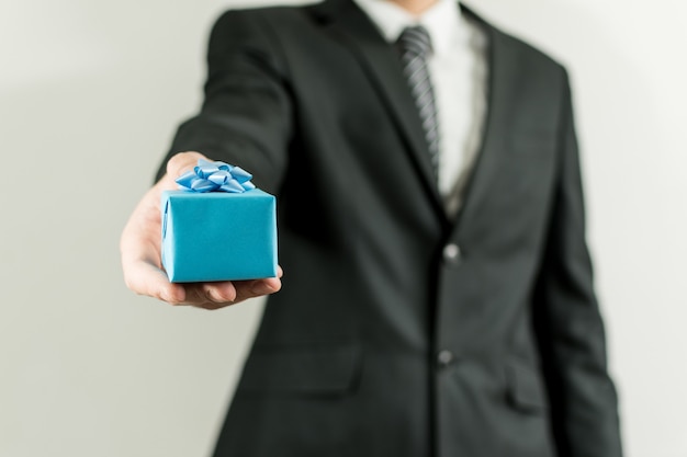 Free photo man in a suit holding a blue small present box