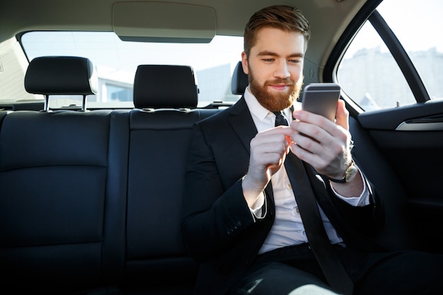 Free Photo man in suit looking at mobile phone in his hand