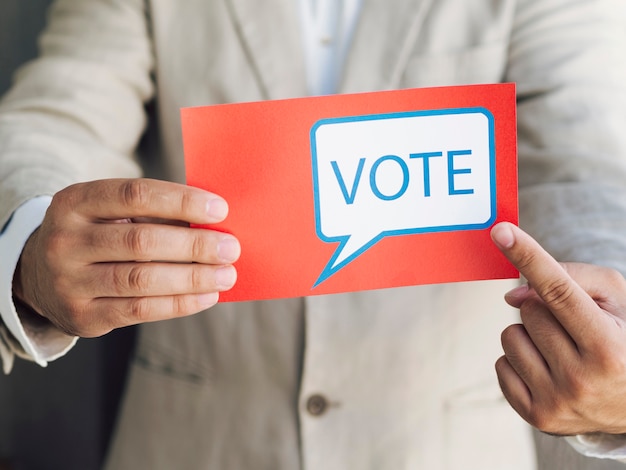 Free photo man in suit pointing to a voting message