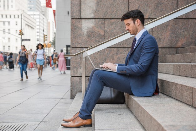 Man in suit using laptop on street