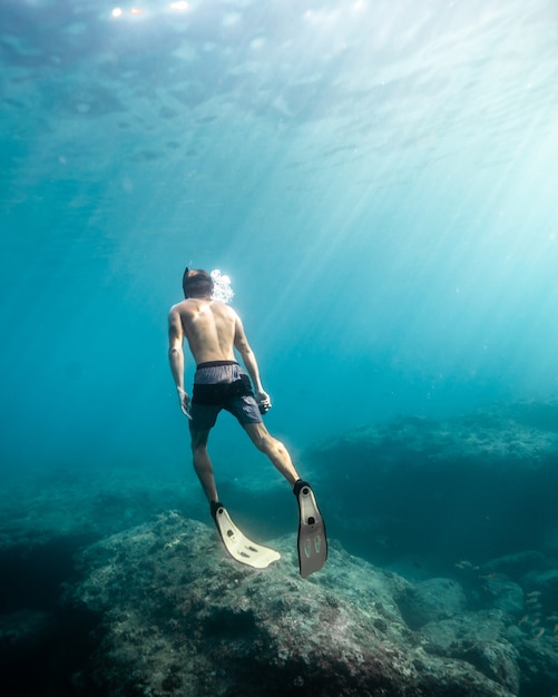 Man swimming under water during a sunny day