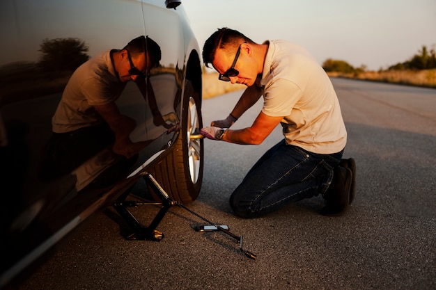 Free Photo man taking off the car wheel