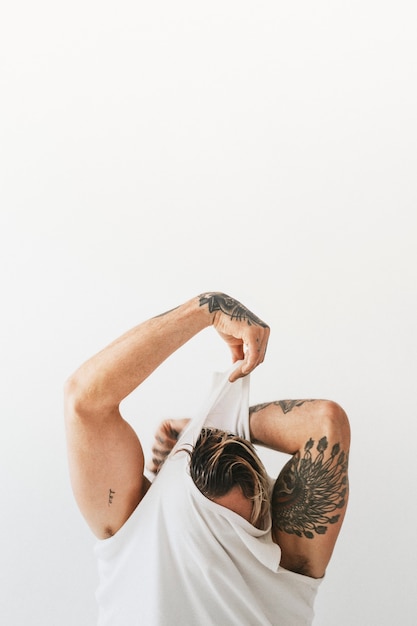 Free Photo man taking off white tank top