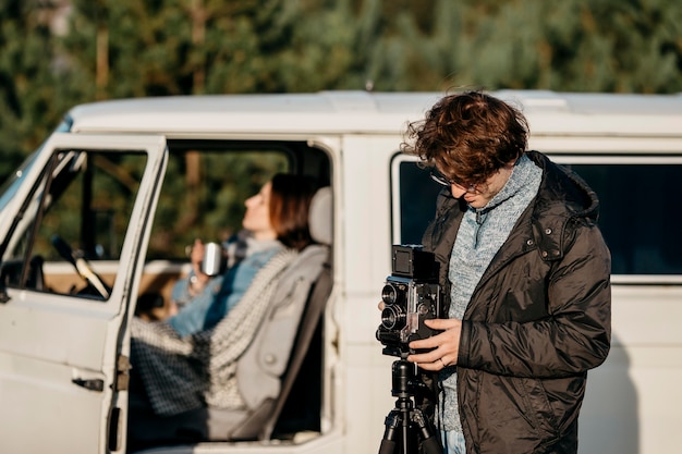 Man taking a photo with a retro camera next to his van