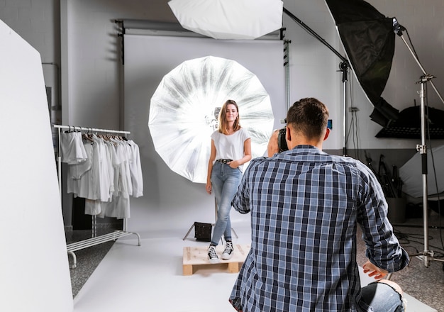 Free Photo man taking a photo of a woman model in studio