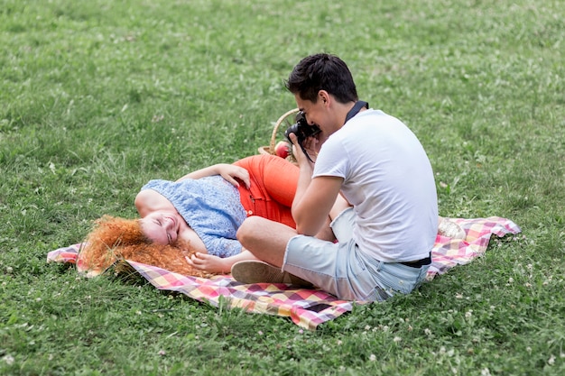 Free photo man taking photos of his girlfriend on grass