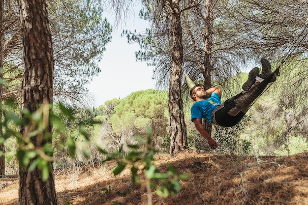 Free photo man taking a rest in hammock in forest