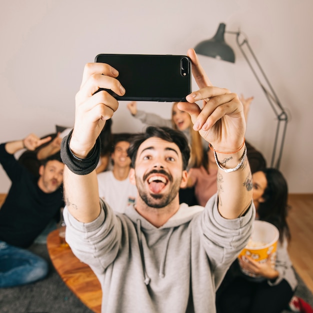 Free photo man taking selfie with friends