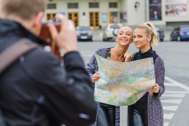 Free photo man taking shot of young pretty tourists