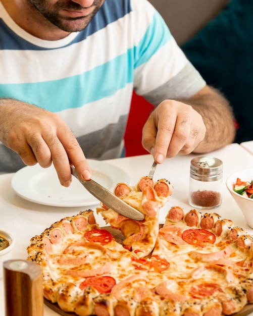 Free photo man taking a slice from sausage pizza