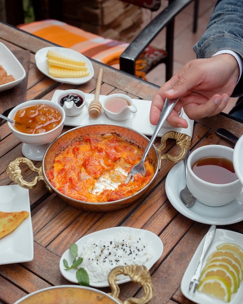 man taking tomato and egg dish with fork at traditional breakfast