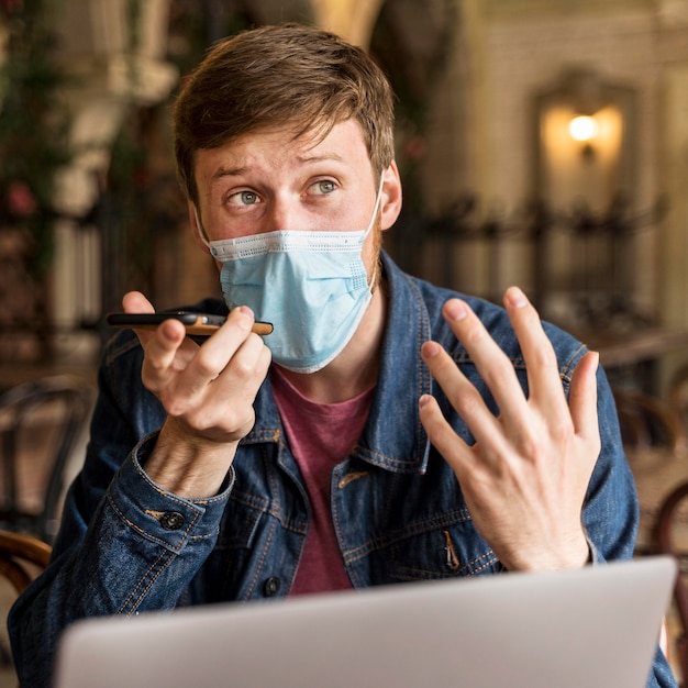 Man talking on the phone indoors while wearing a medical mask