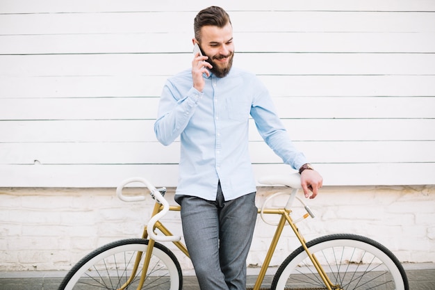 Man talking on phone near white wall