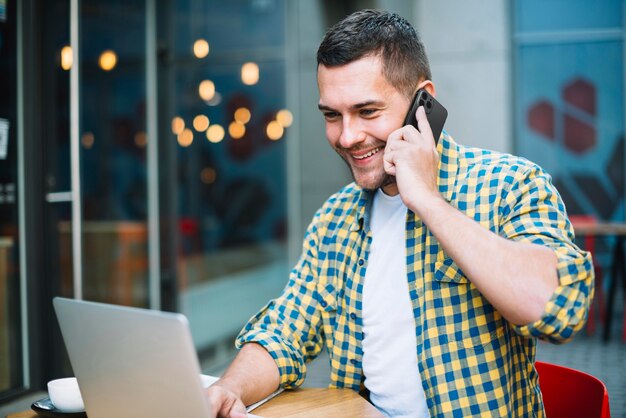 Man talking on the phone while working on his laptop