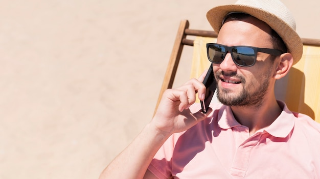 Free photo man talking on smartphone in beach chair