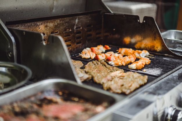 A man in tattoos makes barbecue grill meat outdoors.