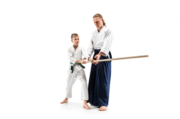 Free photo man and teen boy fighting with wooden sword at aikido training in martial arts school