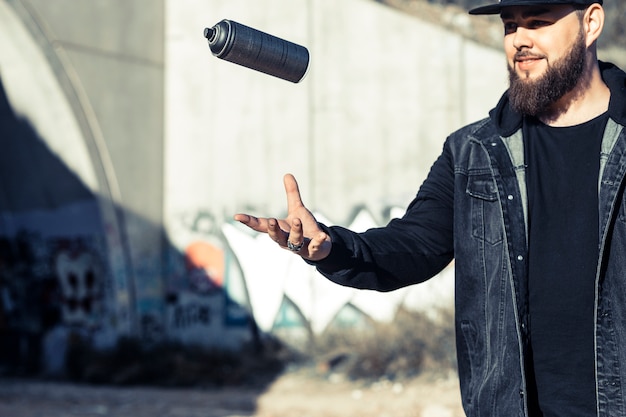 Free photo man throwing aerosol can in mid-air