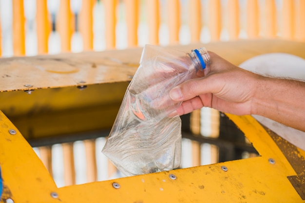 Free photo man throwing plastic bottle in recycle bin