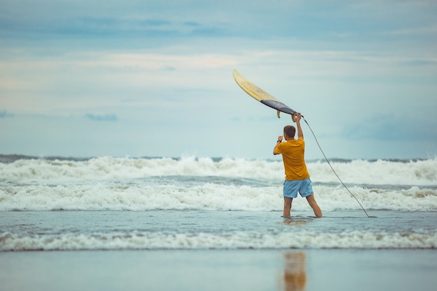 Free photo a man throws a surfboard to the top.