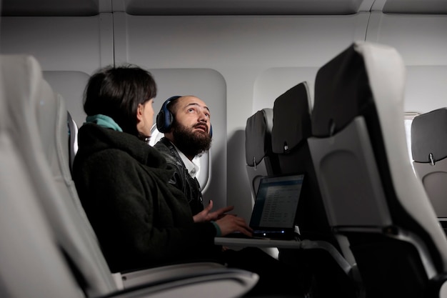 Free photo man tourist preparing to takeoff on airplane flight, getting ready to fly with international airline. travelling in economy class with woman to arrive at holiday destination, air transportation.