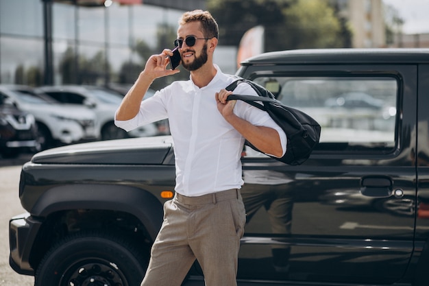 Free photo man travelling with bag and standing by the car