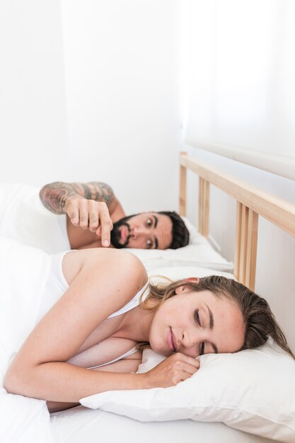 Man trying to wake his wife lying on bed