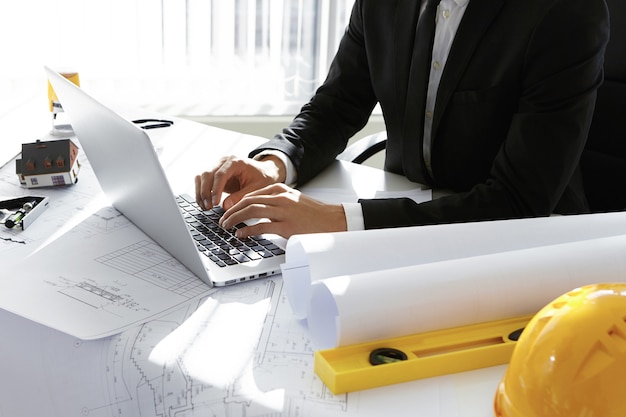 Free Photo man typing on laptop next to engineering tools