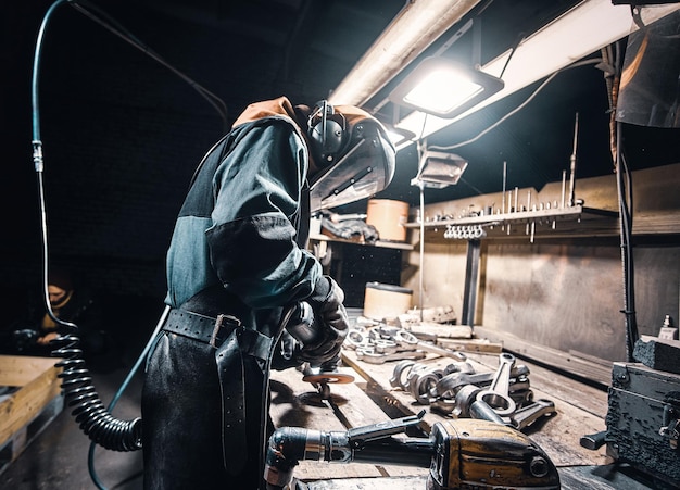 Man in uniform and protective mask is working at metal factory.