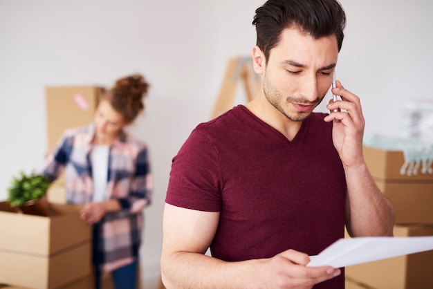 Free photo man using cell phone in his new home