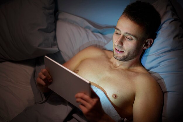 Man using digital tablet before sleep