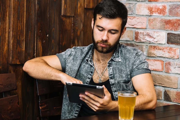 Man using digital tablet with beer on table