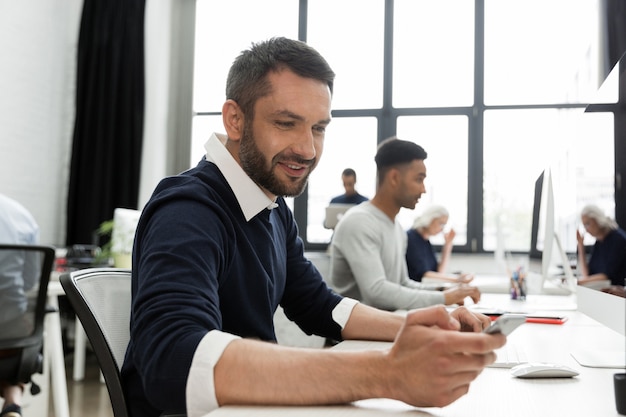 Man using his mobile phone while sitting at his desk