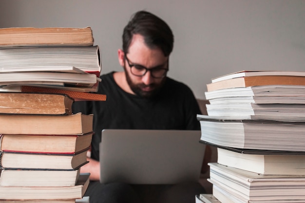 Free photo man using laptop near books