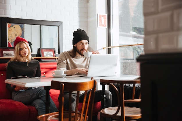 Man using laptop near the girlfriend in cafe