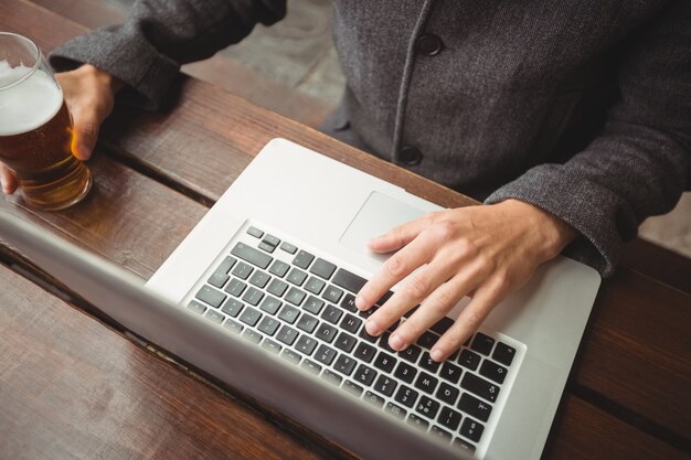 Man using laptop while having glass of beer in bar