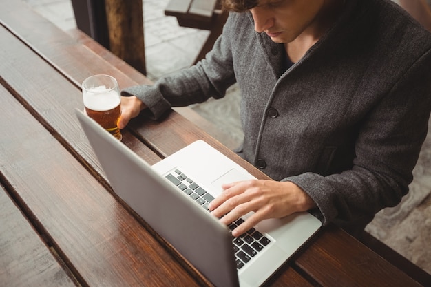 Man using laptop while having glass of beer