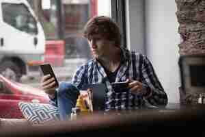 Free photo man using mobile phone while having coffee