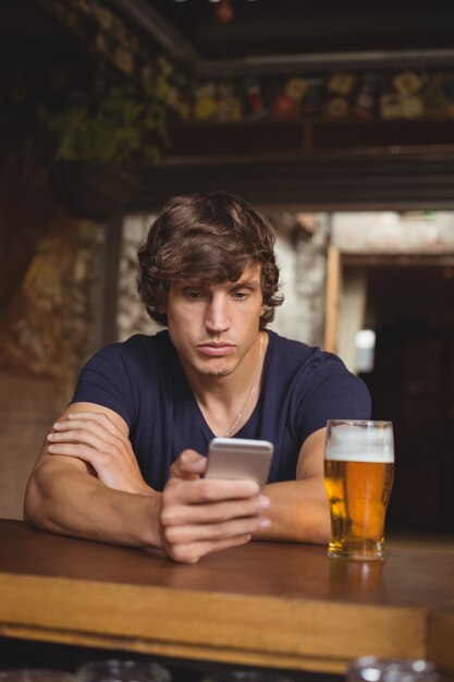 Man using mobile phone with beer glass on table