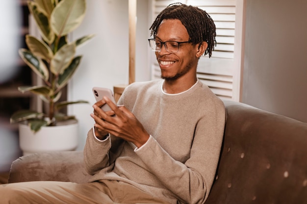 Man using modern smartphone device while on sofa at home