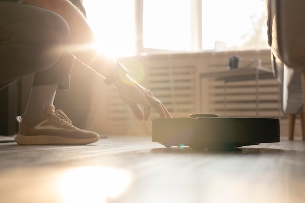 Free photo man using a robot vacuum in the living room