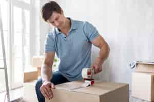 Free photo man using scotch tape on box to secure it for moving out