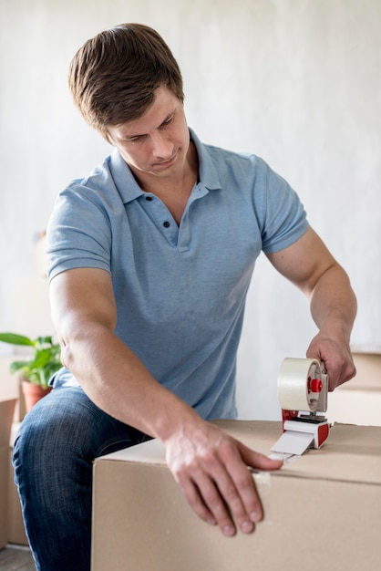 Free photo man using scotch tape to pack box for moving out