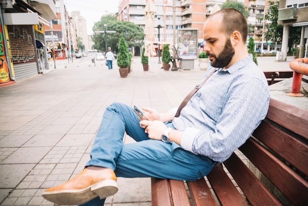 Man using smartphone on bench